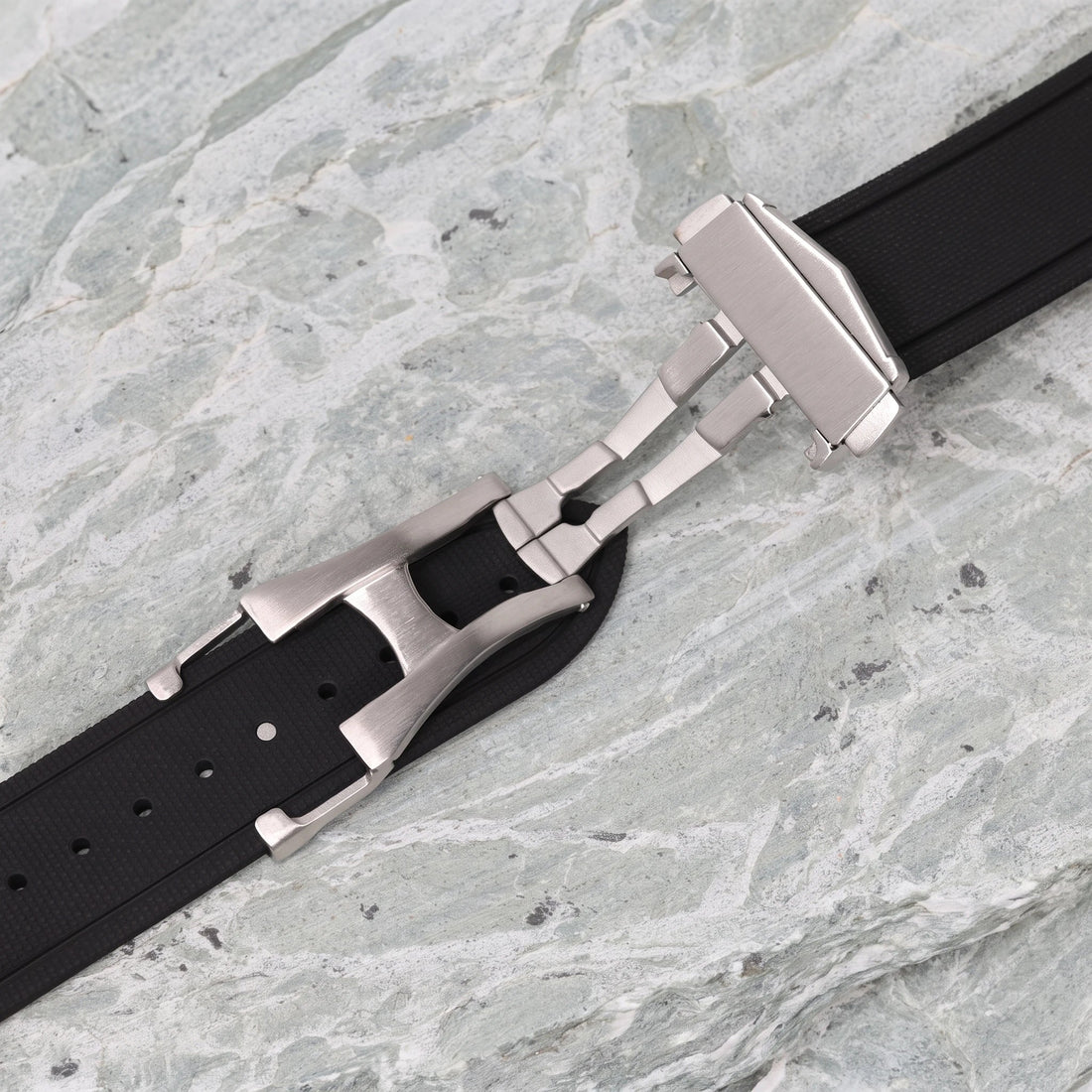 boucle déployante papillon en acier brossé sur un bracelet en caoutchouc noir