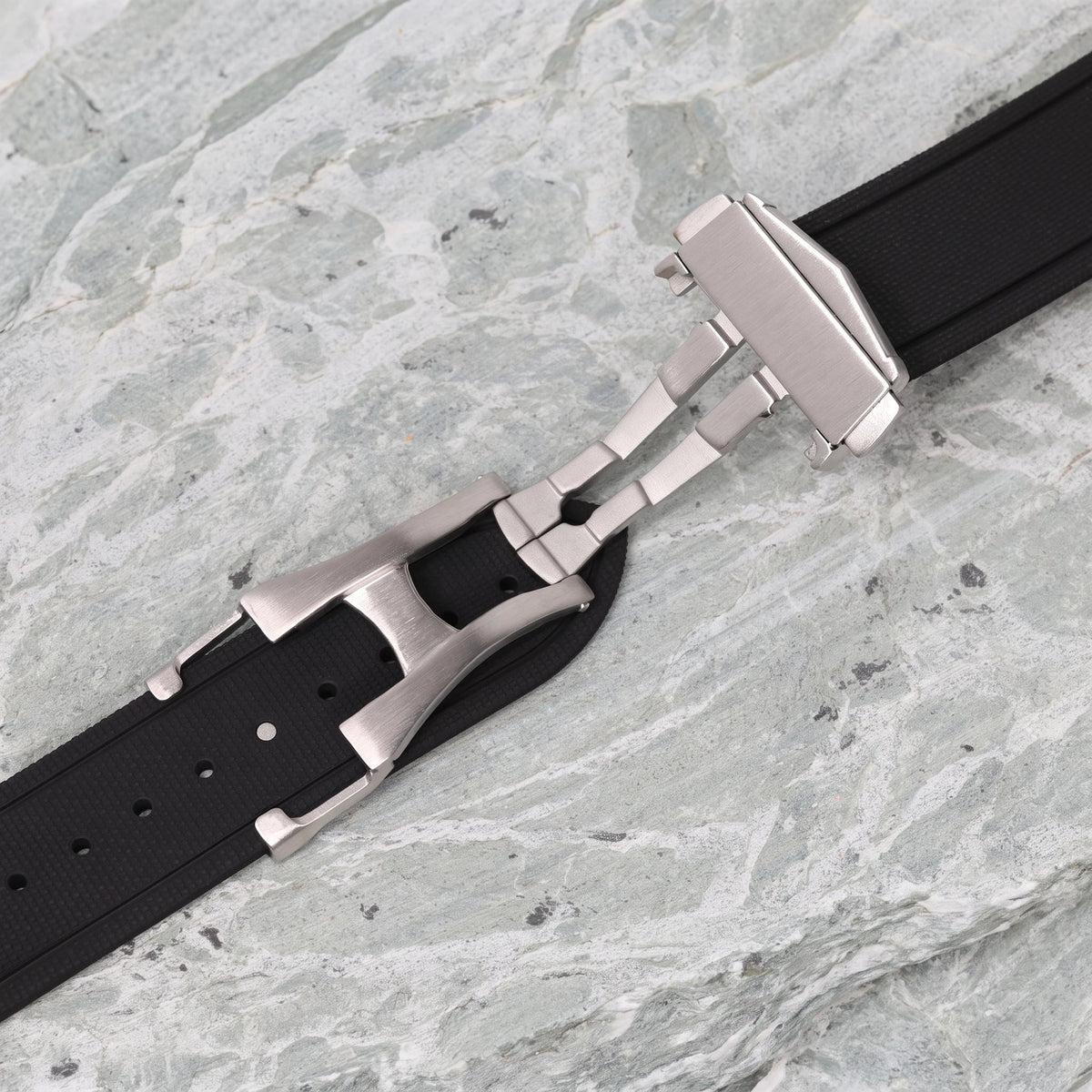 boucle déployante papillon en acier brossé sur un bracelet en caoutchouc noir