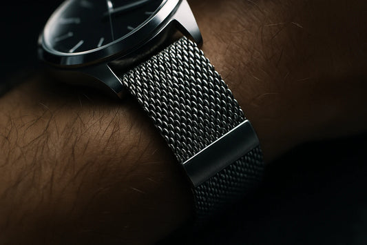 cornes de montre en acier prolongées par un bracelet en maille milanaise au poignet